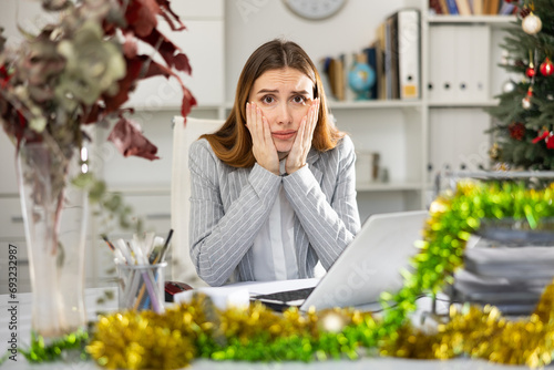 Sad young woman manager working in Christmas decorated office. © JackF