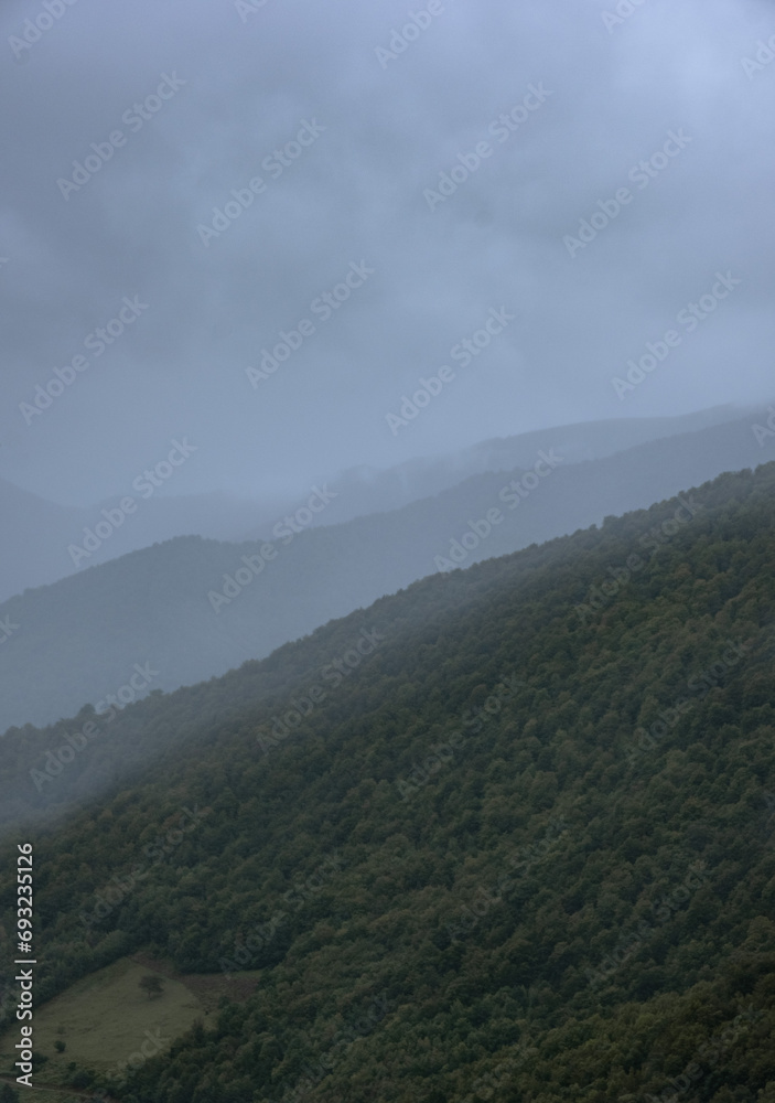 Natural photo of layers of dark sky, mountain range and green forest in Cantabria, picos da europa, leon, asturias, spain