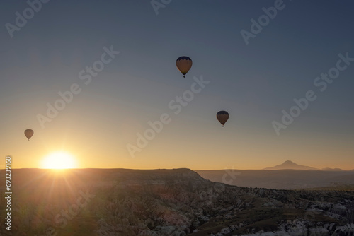three hot air balloons flying in cappadocia at sunrise, at the Goreme air field at dawn, Erciyes volcano in the background, Cappadocia, Turkey, copy space