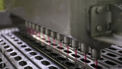 Industrial ice cream production process and manufacturing. Technology and automation. Closeup view of a commercial popsicle production machine filling the ice pop molds with strawberry flavor. photo