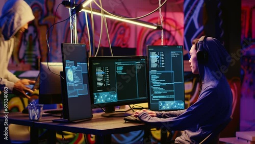 Hackers in secret bunker with graffiti walls writing code that spoofs their location, tricking cops. Rogue programmers running script pinging wrong location to cybercriminal law enforcement photo