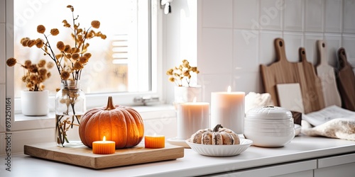 Autumn decorations in a white Scandi-style kitchen with pumpkin, candles, and a tray.