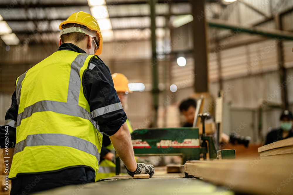 man cleaning timber wood in dark warehouse industry. Team worker carpenter wearing safety uniform and hard hat working and checking the quality of wooden products at workshop manufacturing. man cleaning timber wood in dark warehouse industry. Team worker carpenter wearing safety uniform and hard hat working and checking the quality of wooden products at workshop manufacturing.