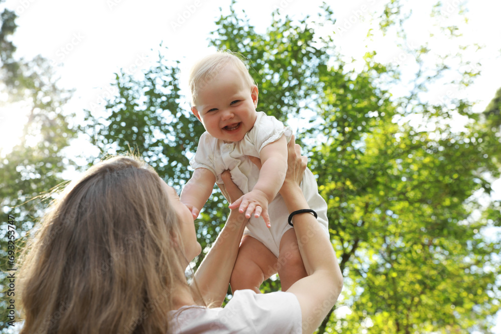 Mother with her cute baby spending time together outdoors, low angle view Mother with her cute baby spending time together outdoors, low angle view