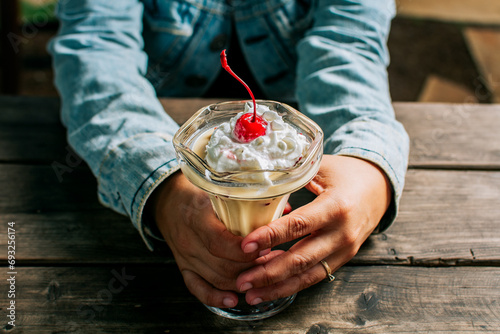 Female hand holding cherry milkshake on wooden table. Person holding cherry smoothie over wooden table|