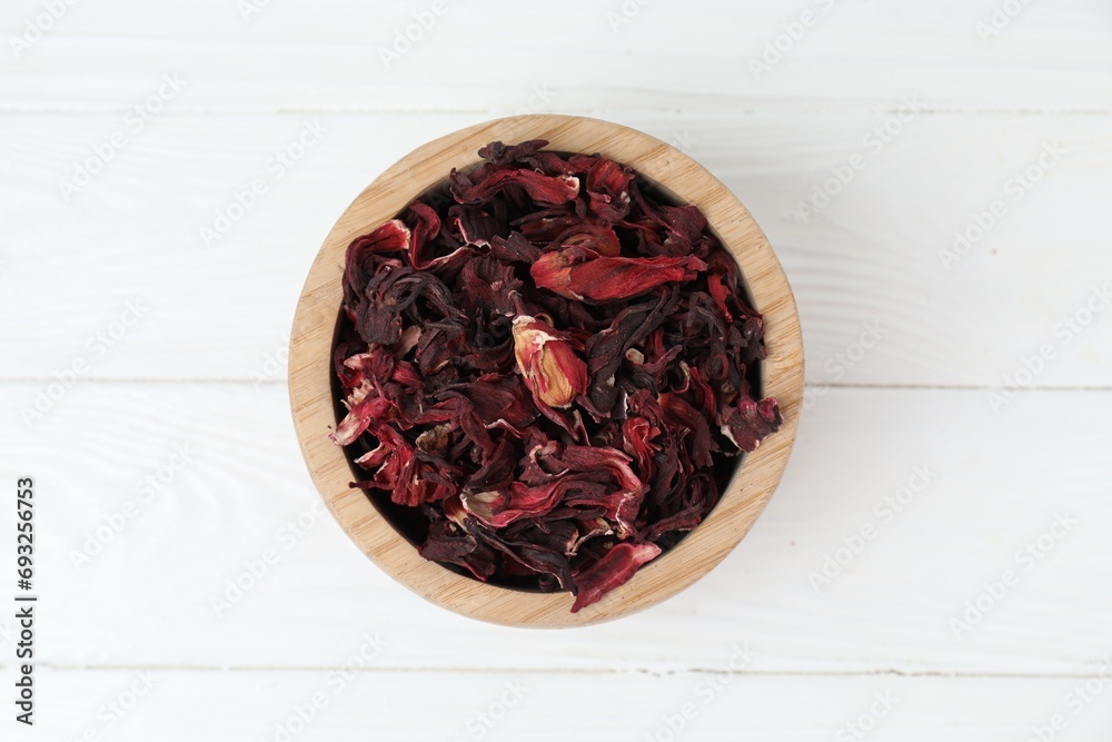 Hibiscus tea. Bowl with dried roselle calyces on white wooden table, top view Hibiscus tea. Bowl with dried roselle calyces on white wooden table, top view