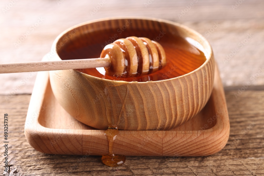 Delicious honey in bowl and dipper on wooden table, closeup Delicious honey in bowl and dipper on wooden table, closeup