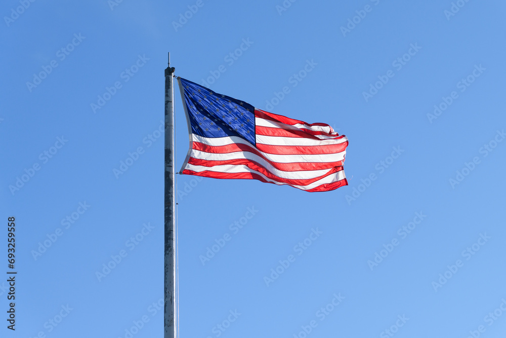 Stars and stripes flag of the United States of America against clear blue sky
