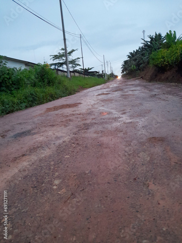 Dirt road - a road in an oil palm plantation, showing oil palm plantations on the left and right of the road, the road looks muddy and muddy because of the rain. photo