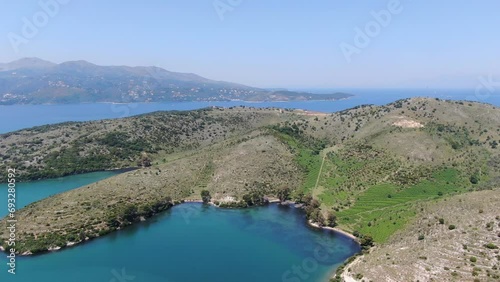 Drone view in Albania flying over blue sea sorrunded by green landscape hills with mountains on the back photo