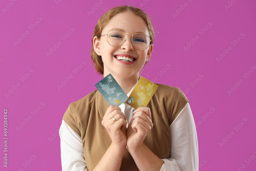 Young businesswoman with credit cards on purple background Young businesswoman with credit cards on purple background