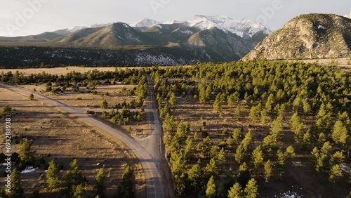 Drone retreating from Mount Antero down a lonely road with pine trees on both sides during sunset photo