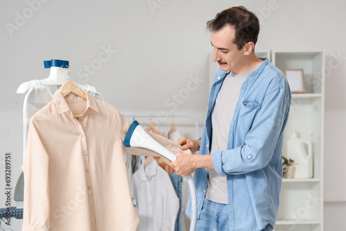 Young man steaming clothes ...