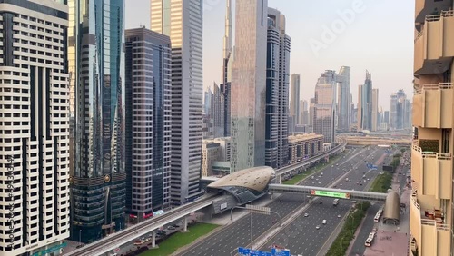 Sheikh Zayed Road in Dubai, where cars flow seamlessly beneath the towering skyscrapers that grace the city skyline. Amidst the bustling traffic, witness the iconic Burj Khalifa photo