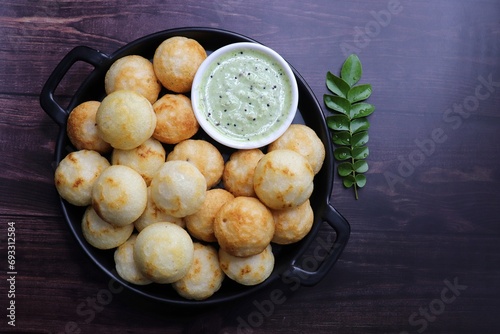 Paniyaram are savory balls made using fermented rice and urad dal batter along with tempered onion and spices. Also known as Paddu, Ponganalu, Kuli, bugga, and appe. served with coconut chutney photo