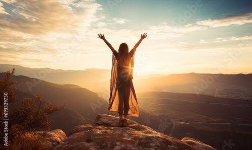 A woman standing on top of a mountain with her arms in the air photo