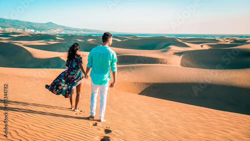 couple walking at the beach of Maspalomas Gran Canaria Spain, men and woman at the dunes desert of Maspalomas Spain Europe in the morning sun photo