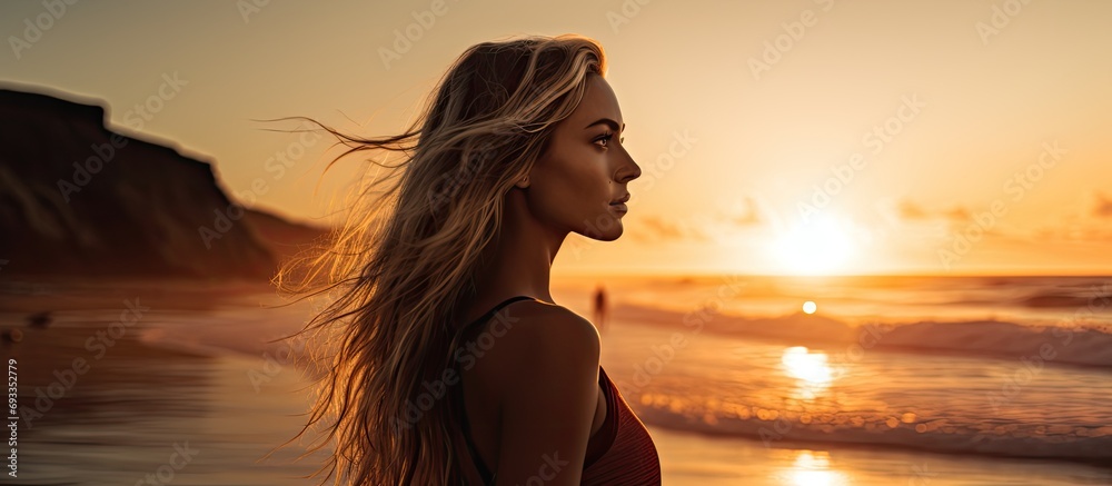 Gorgeous surfer girl by the beach during sunset.