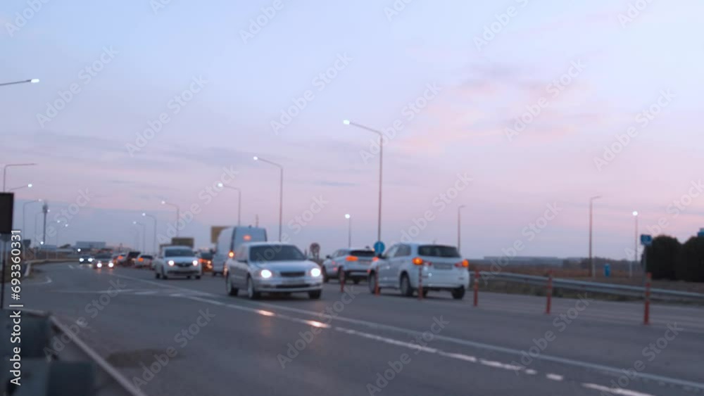 Cars Buses Trucks Driving with Burning Headlights on an Asphalt Road at Sunset Time Lapse. Beautiful Colorful Sky and Highway Traffic. Transport Fast driving along the Evening Highway. Cars Buses Trucks Driving with Burning Headlights on an Asphalt Road at Sunset Time Lapse. Beautiful Colorful Sky and Highway Traffic. Transport Fast driving along the Evening Highway.