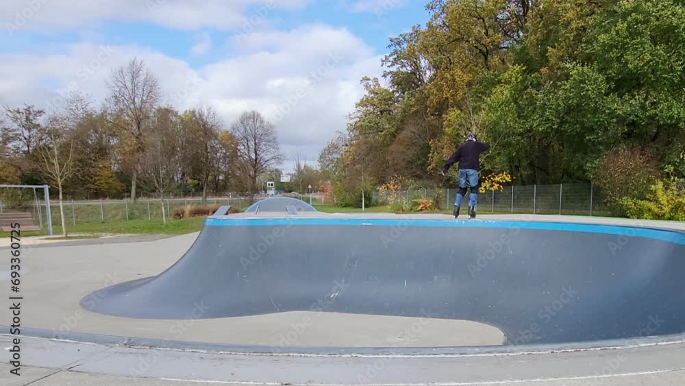 Ein Mann, der mit Inlineskates auf einer Halfpipe in einem Skatepark fährt. Der Mann trägt einen Helm und führt einen Trick aus. Die Rampe ist aus Holz und gebogen.