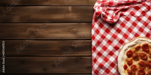 Vintage wooden background with red and white textile, providing copy space for text, displays cooking food, particularly pizza, on a wooden table.