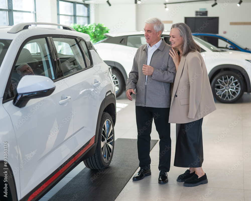 An elderly Caucasian couple chooses a new car at a car dealership. An elderly Caucasian couple chooses a new car at a car dealership.