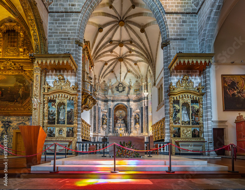 Altar and chapels inside the medieval church of San Francisco, part of the Chapel of Bones. Altar with saints and crucified Jesus Christ with colored lighting. photo