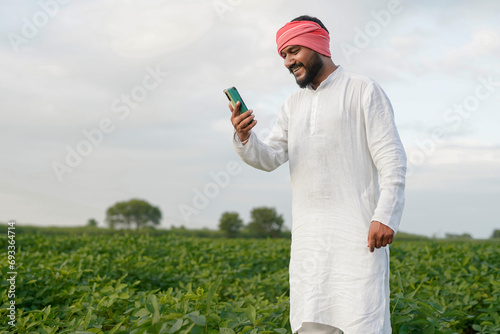 Indian farmer using smart phone at green farm field