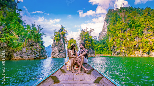 a couple traveling by longtail boat exploring epic limestone cliffs in a huge lake in Khao Sok National Park, Chiew Lan Lake, Thailand Surat Thani photo