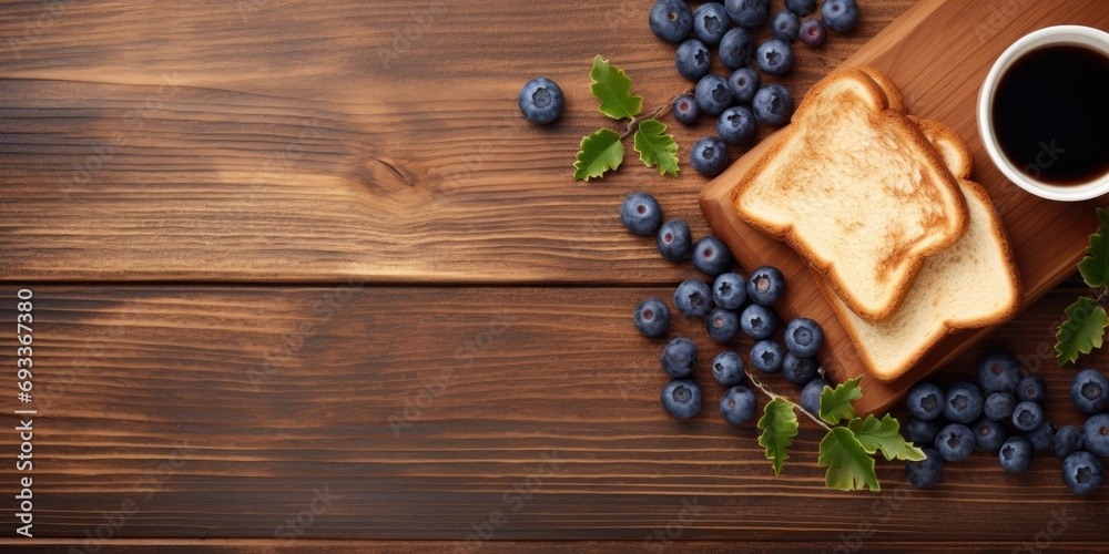 Tasty toasts with butter, blueberries, and coffee on a wooden table, top view.