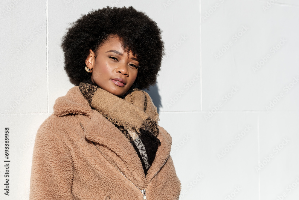 Confident young model looking at camera leaning on a white wall outdoors. Confident young model looking at camera leaning on a white wall outdoors.