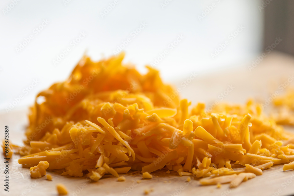 Shredded Cheddar Cheese on Wooden Board Close-Up Shredded Cheddar Cheese on Wooden Board Close-Up