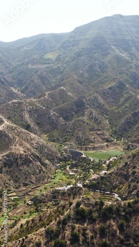 Farm in the middle of a green valley with small water reservoir