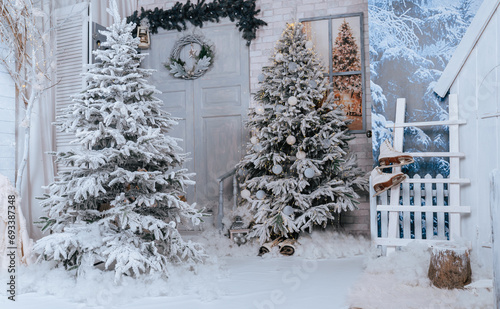 Background of snow-covered fir trees. Studio decor. Door and snow-covered porch against a background of winter trees