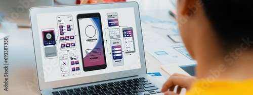Panorama banner of startup UX developer or company employee design user interface or UI prototype for mobile application or website software with software display on laptop monitor in office. Synergic photo