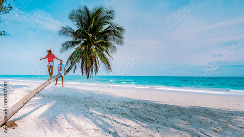 A couple climbing in a palm tree in Thailand, Wua Laen beach Chumphon area Thailand, palm tree hanging over the beach with a couple of men and woman on vacation in Thailand © Fokke Baarssen
