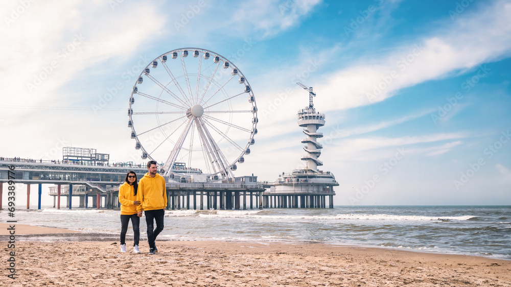 a couple of men and woman on the beach of Scheveningen Netherlands during Spring, The Ferris Wheel at The Pier at Scheveningen in the Netherlands, Sunny spring day at the beach of Holland
