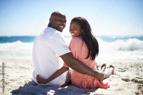 Rear, portrait and smile with a black couple on the beach for travel, romance or adventure together. Summer, love or dating with a happy young man and woman sitting on the sand by the ocean or sea