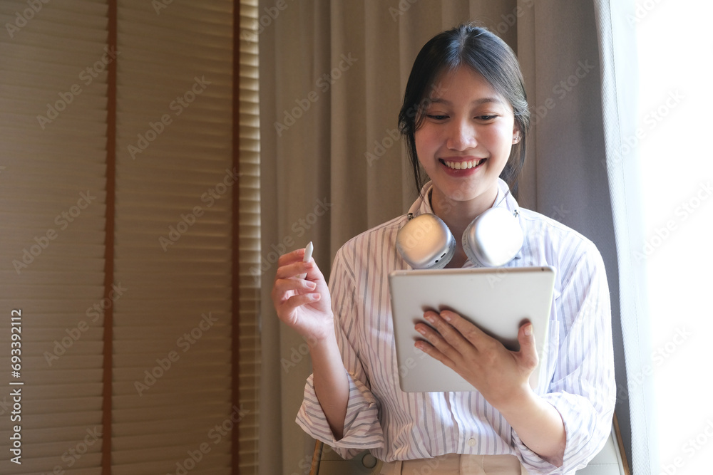 Attractive millennial Asian woman using her digital tablet in the coffee shop. remote working, urban lifestyle concept Attractive millennial Asian woman using her digital tablet in the coffee shop. remote working, urban lifestyle concept