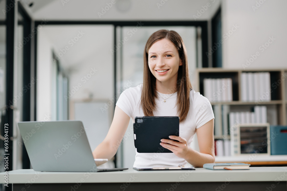 Confident business expert attractive smiling young woman holding digital tablet  on desk in office..