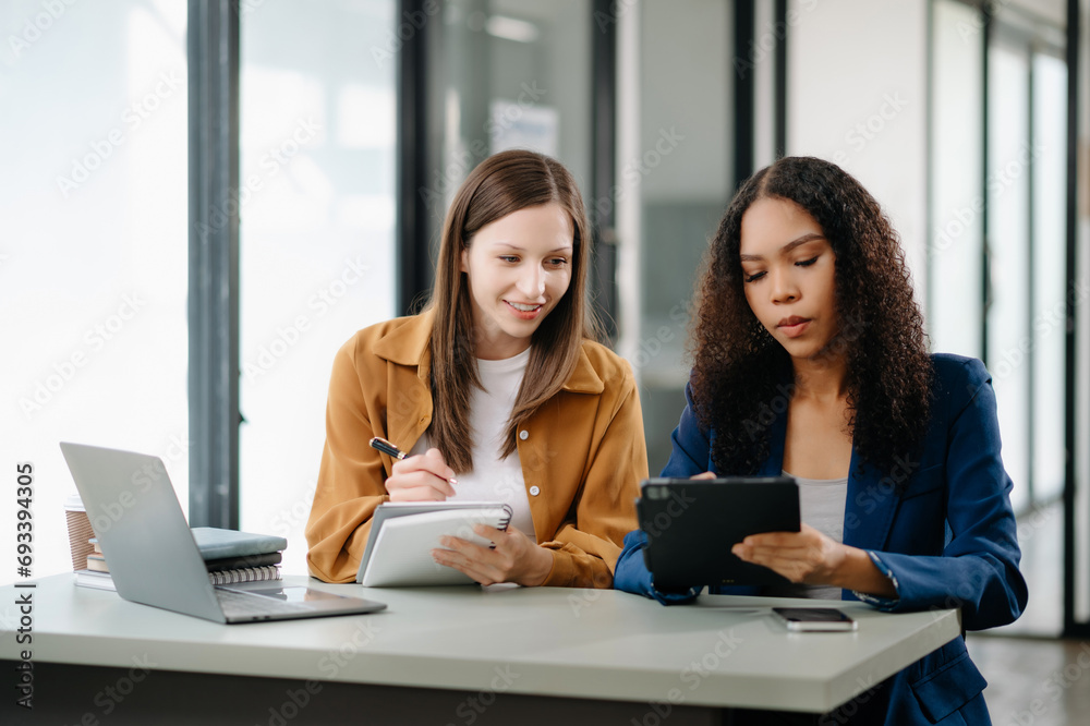 Two business workers talking on the smartphone tablet and using laptop at office...