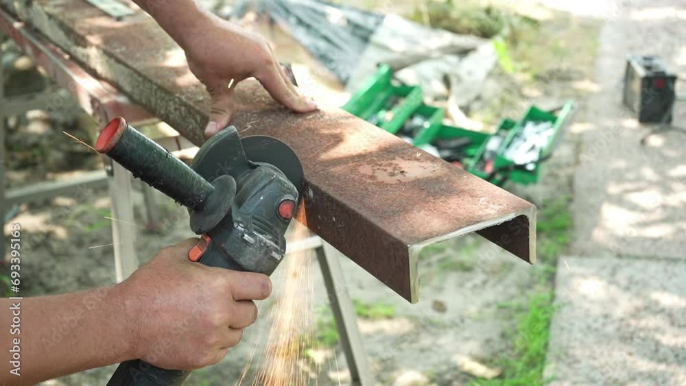 Worker cutting metal tube using an Angle Grinder. Bright sparks and flashes Worker cutting metal tube using an Angle Grinder. Bright sparks and flashes