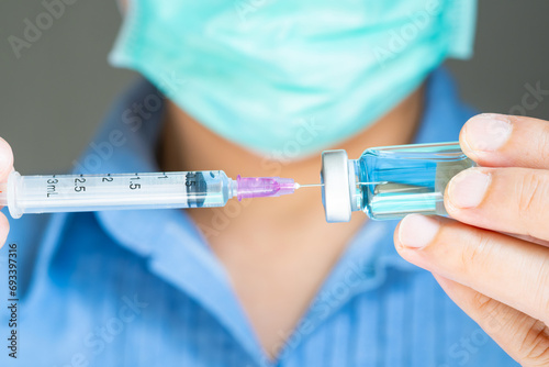 doctor's hand holds a syringe and a blue vaccine bottle at the hospital. Health and medical concepts 