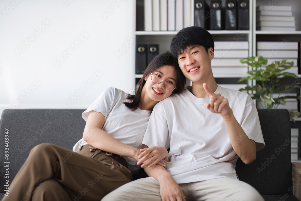 A smiling young couple of boys and girls were sitting on the sofa in the living room, teasing each other with fun. A smiling young couple of boys and girls were sitting on the sofa in the living room, teasing each other with fun.