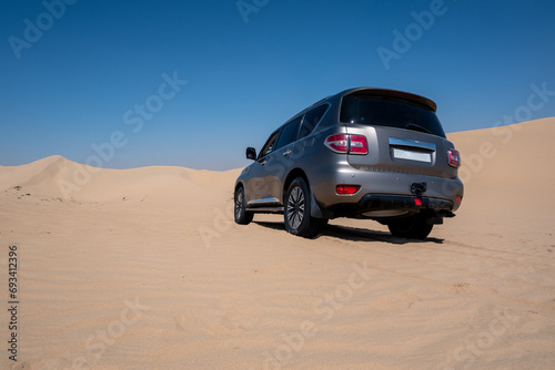 SUV four wheel drive vehicle car Al Qudra empty quarter seamless desert sahara in Dubai UAE middle east with wind paths and sand hills gray cloudy sky photo