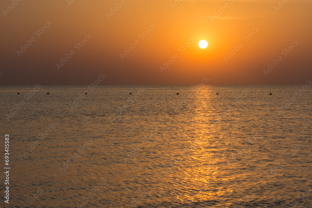 warm sunrise with reflections in the sea with waves and buoys