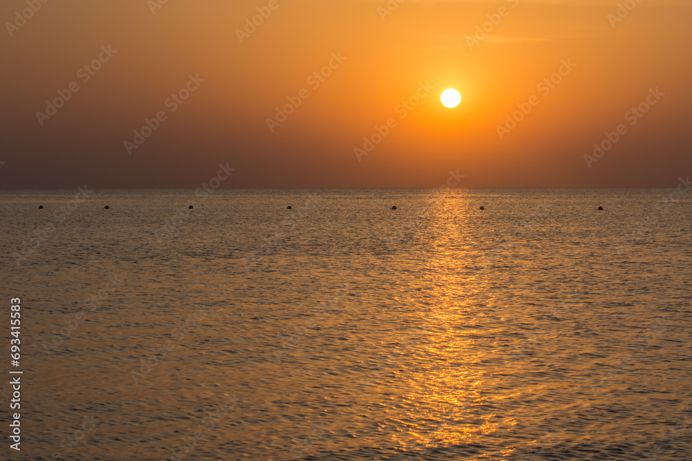 Obraz premium warm sunrise with reflections in the sea with waves and buoys