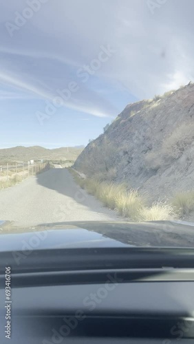 First person view, FPV, from dashcam of car driving on narrow back road in Tabernas desert, Almeria, Andalusia, Spain, Europe. Road trip vertical video in POV in arid, dry climate photo