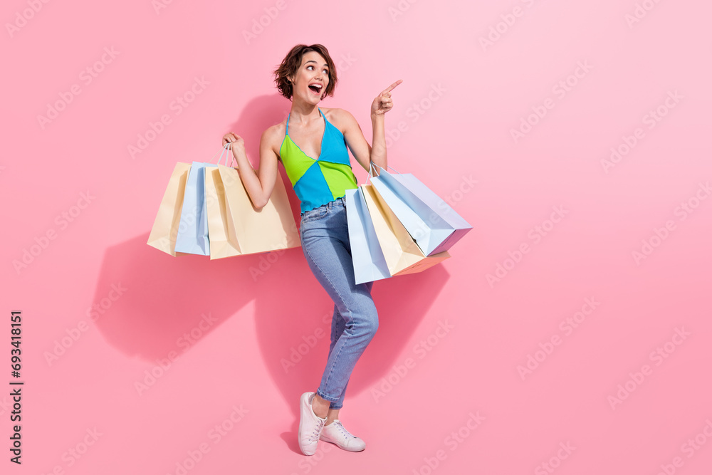 Full length photo of funky woman pointing finger empty space excited recommend brand store in her town isolated over pink color background