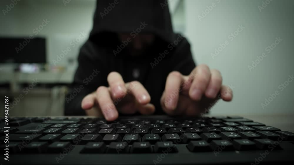 Unrecognizable man hacker wearing sweatshirt with hood typing on laptop ...